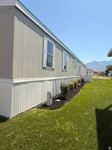 Light-colored siding with white window shutters and trim, complemented by a manicured lawn