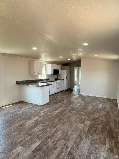 Kitchen featuring white cabinetry, granite countertops, white appliances, and wood-finish tile flooring