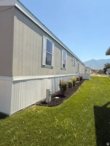 Light-colored siding with white window shutters and trim, complemented by a manicured lawn
