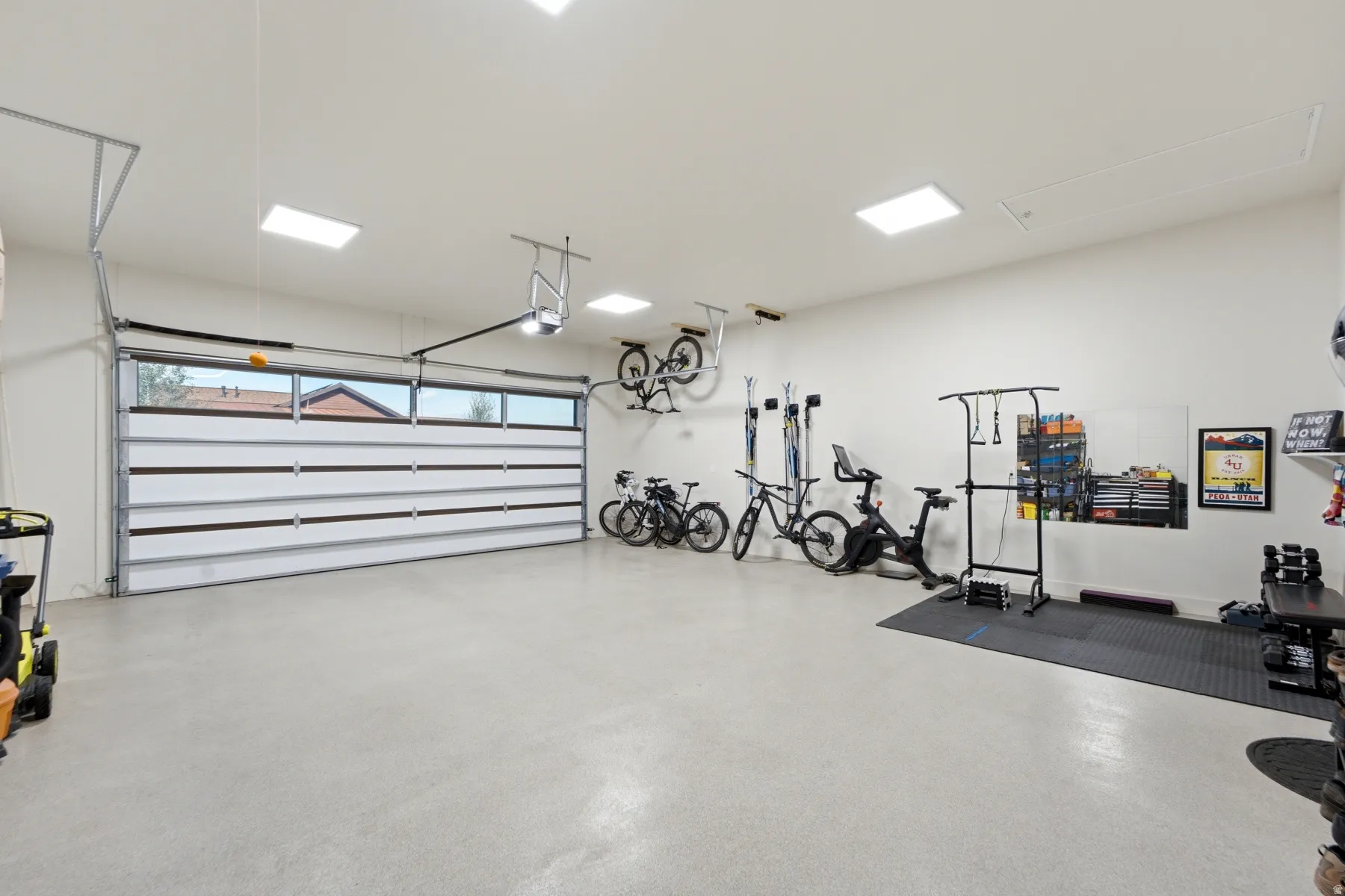 Spacious garage with light-toned flooring, white walls, and a modern garage door featuring horizontal windows