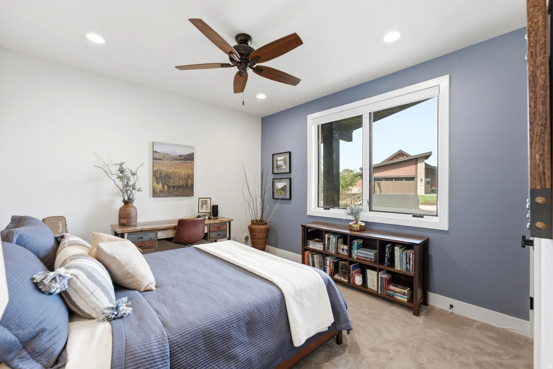 Recessed ceiling lighting, wood-finish ceiling fan, expansive window, light-toned carpeting, and a built-in desk area