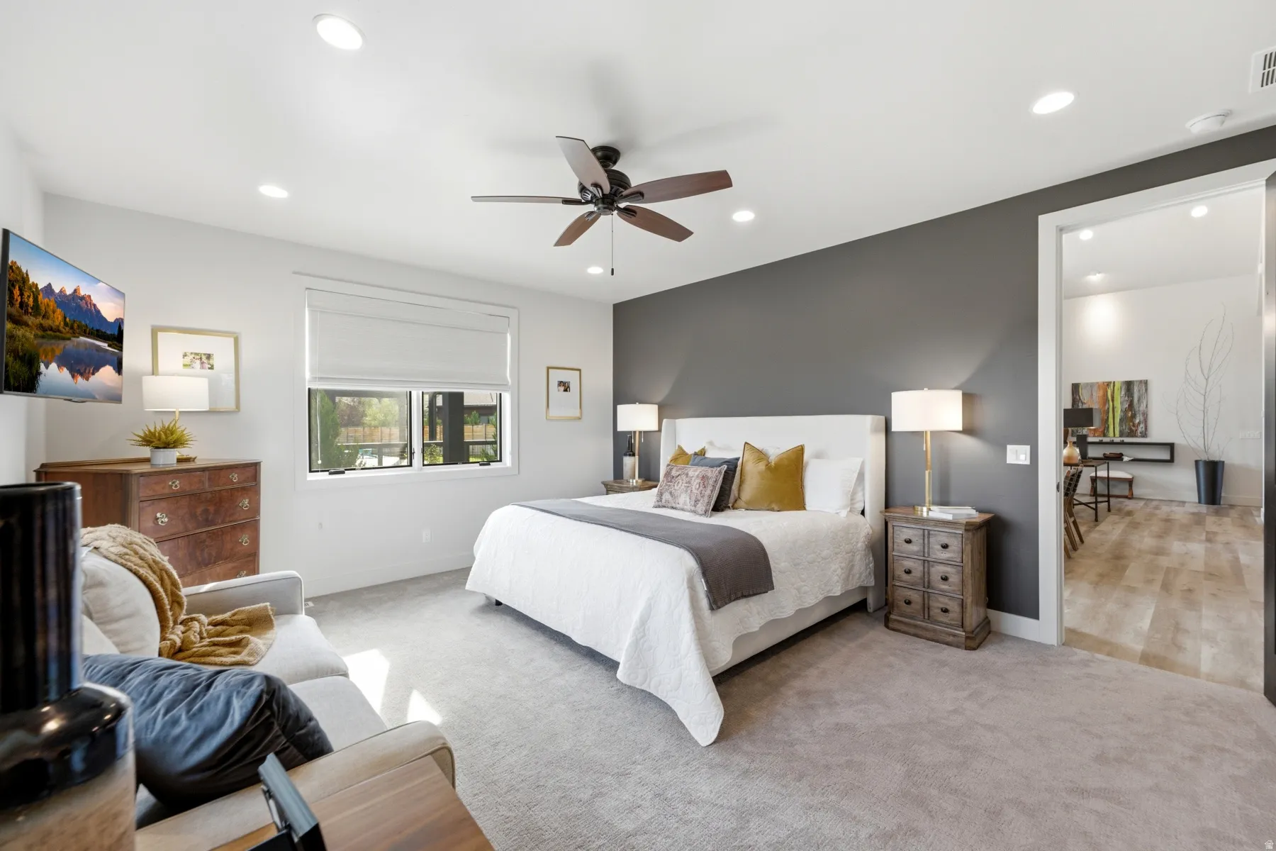 Recessed lighting, ceiling fan, carpeting, window with roller shade, and a door opening to an adjacent room with wood-finish flooring