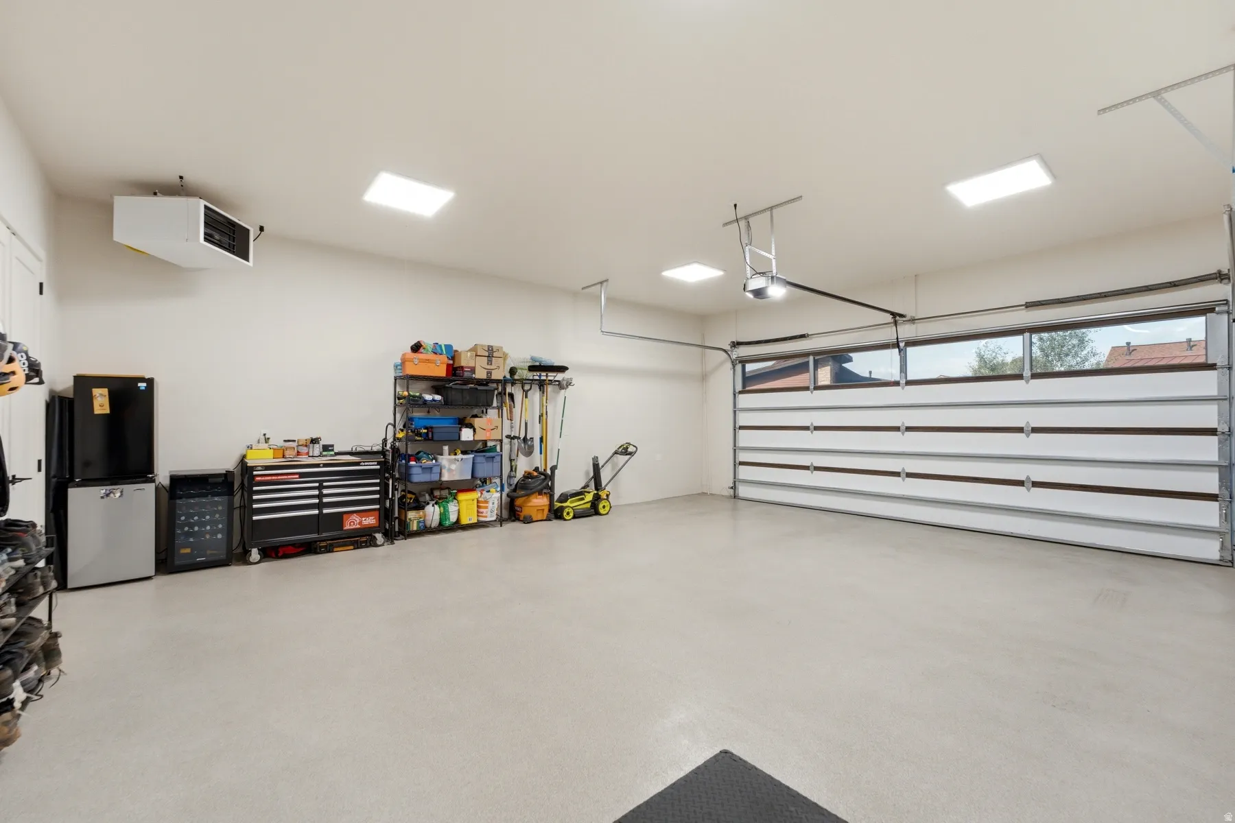 Attached garage with coated concrete flooring, overhead radiant heater, and a garage door with integrated windows