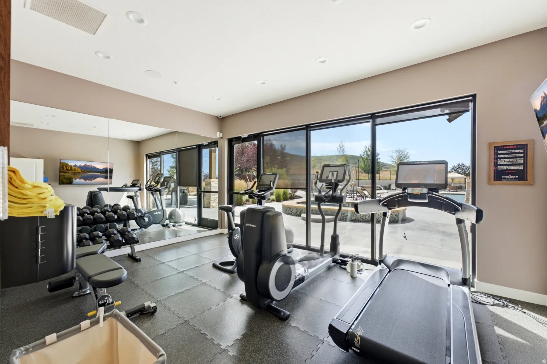 Dedicated fitness area with rubber flooring, full-height wall mirror, and recessed lighting