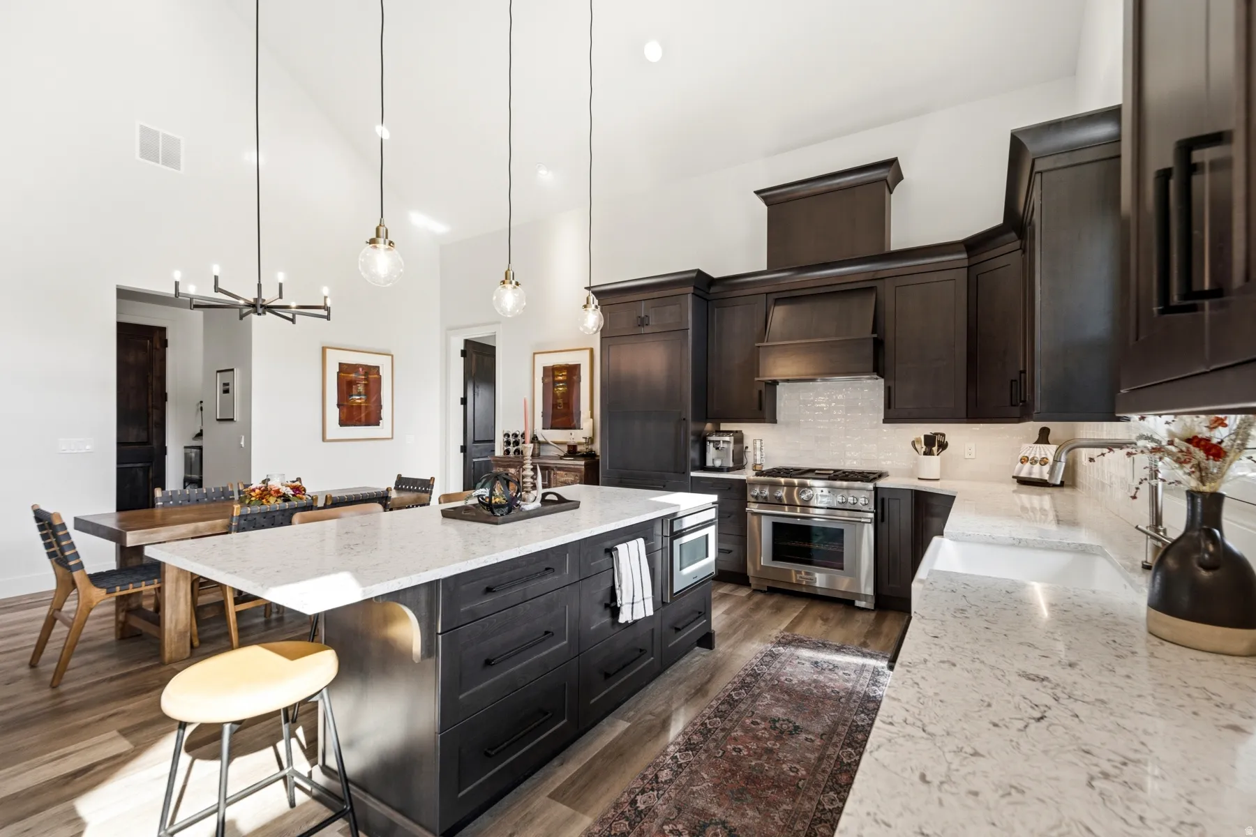 Kitchen featuring dark wood cabinetry, light-toned countertops, stainless steel appliances, a tiled backsplash, and wood-finish flooring
