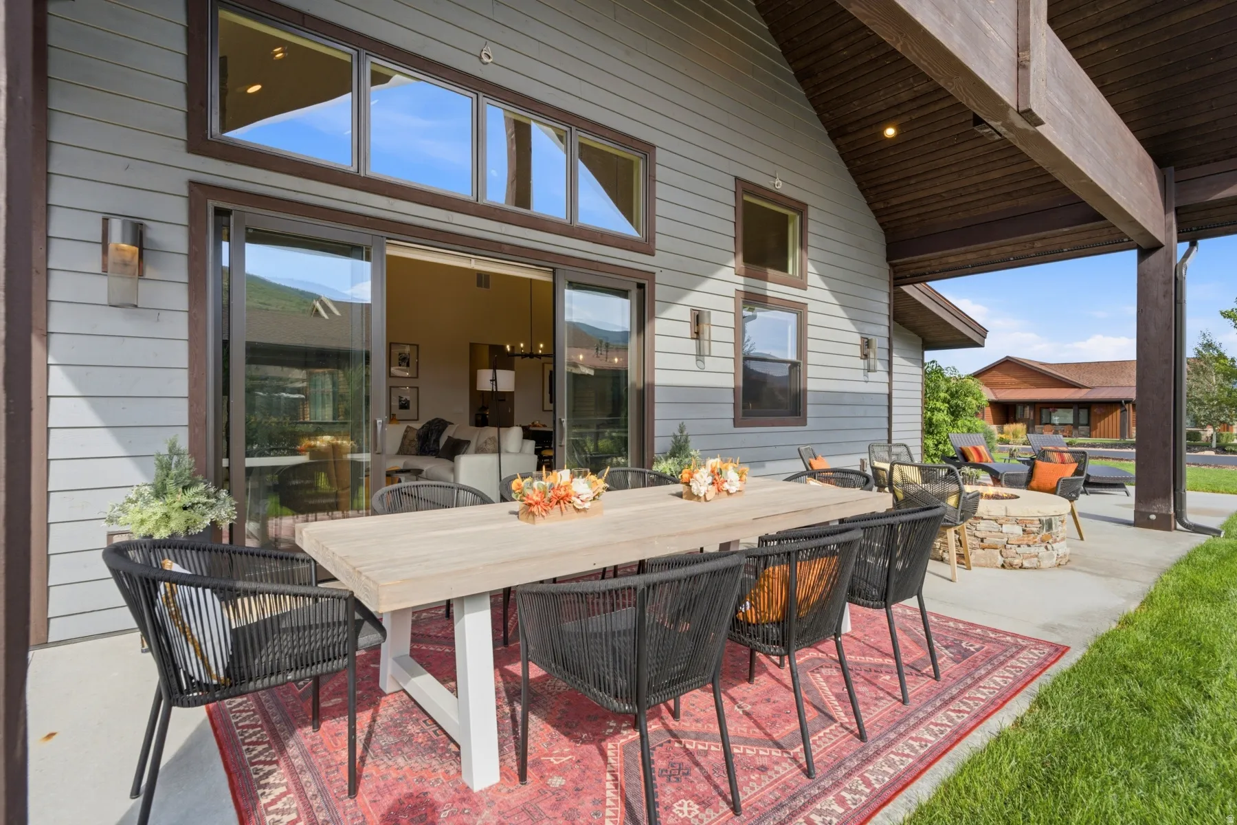 Covered patio with a stone fire pit, concrete flooring, and wooden beam accents