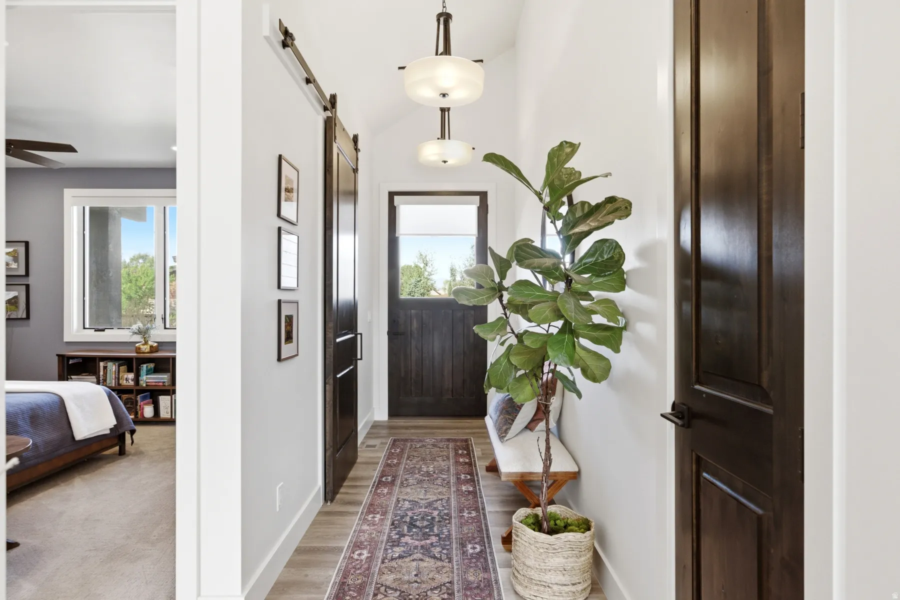 Wood-finish flooring, dark wood-tone barn door, and a paneled entry door with transom window