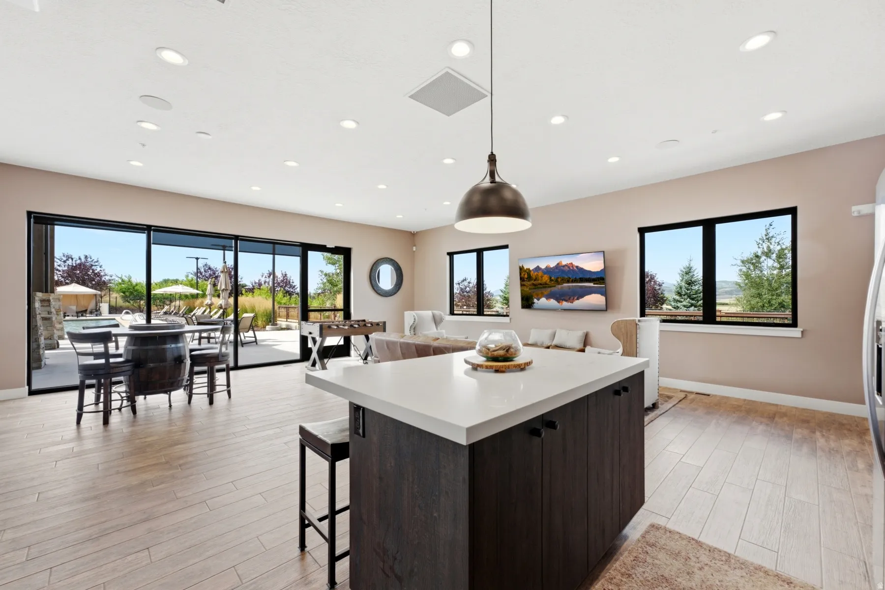 Spacious interior featuring a large kitchen island with a light-toned countertop, wood-finish flooring, and recessed lighting