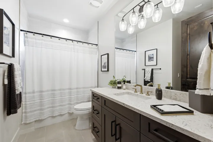 Vanity with a light-toned countertop and integrated sink, dark wood-finish cabinetry, and an elongated mirror