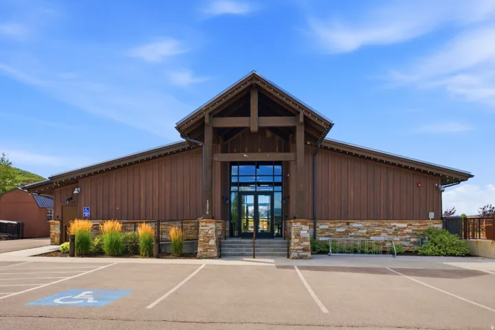 Building exterior featuring wood siding, stone accents, and a prominent entrance with glass doors