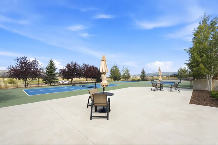 Paved patio area, two tennis courts, perimeter fencing, and mature trees