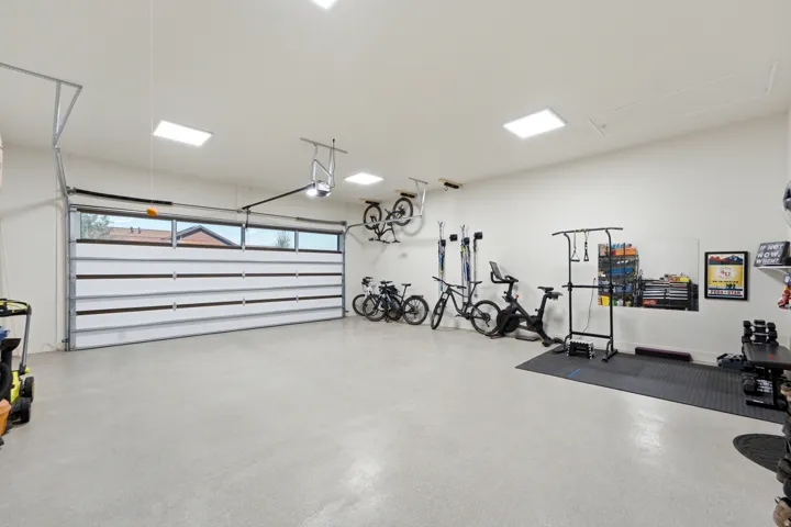 Spacious garage with light-toned flooring, white walls, and a modern garage door featuring horizontal windows