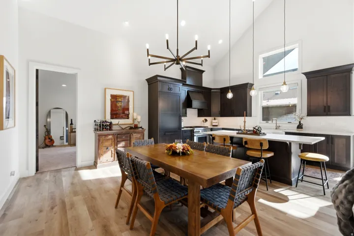 Vaulted ceilings, wood-finish flooring, dark wood cabinetry, a center island with seating, and a large window above the sink