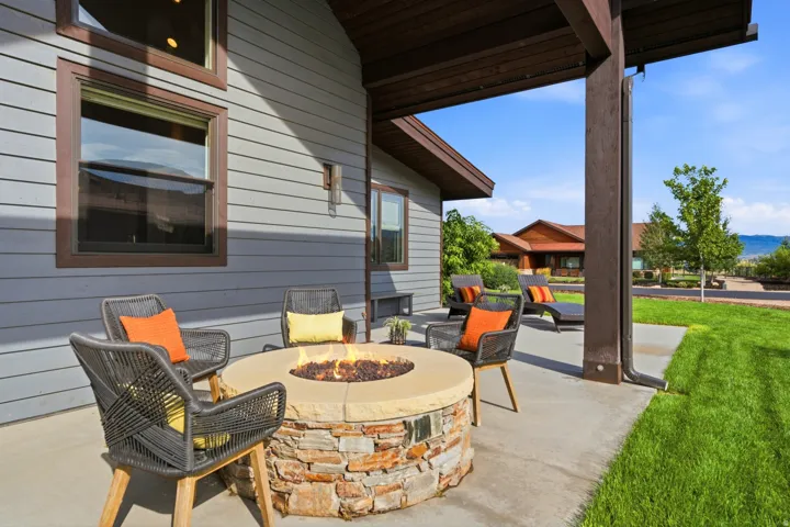Concrete patio featuring a stacked stone fire pit and a pergola structure