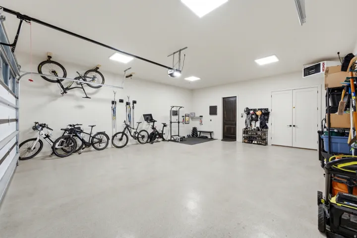 Spacious garage with light grey epoxy flooring, recessed ceiling lighting, and a dark wood-paneled door