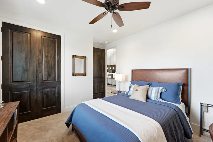 Wood-finish bi-fold closet doors, recessed lighting, and a ceiling fan