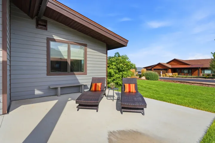 Concrete patio with a built-in bench and a manicured lawn