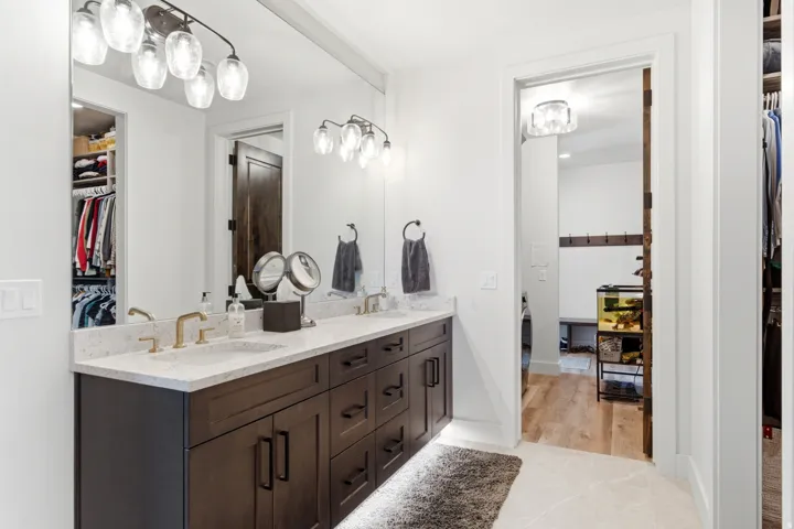 Double vanity with undermount sinks, light-toned countertop, and gold-finish fixtures