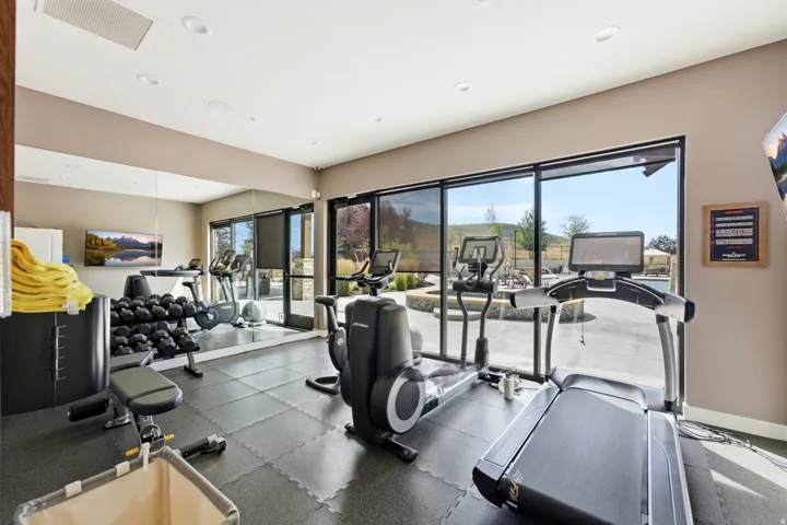 Dedicated fitness area with rubber flooring, full-height wall mirror, and recessed lighting