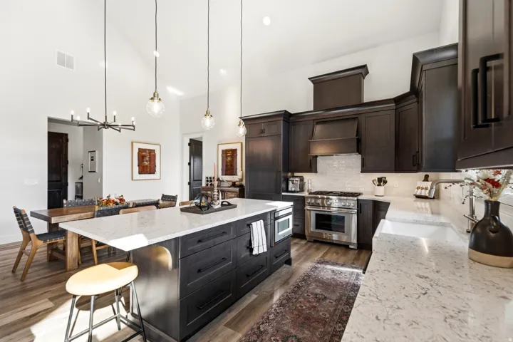 Kitchen featuring dark wood cabinetry, light-toned countertops, stainless steel appliances, a tiled backsplash, and wood-finish flooring