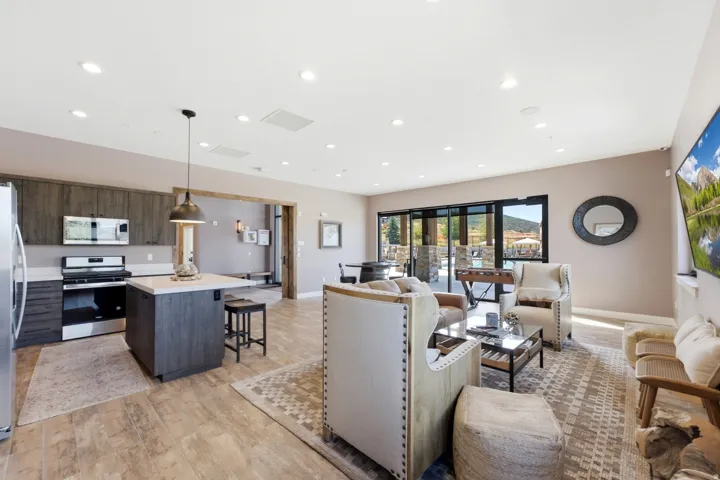 Recessed lighting, wood-finish flooring, stainless steel appliances, kitchen island with seating, and expansive glass doors