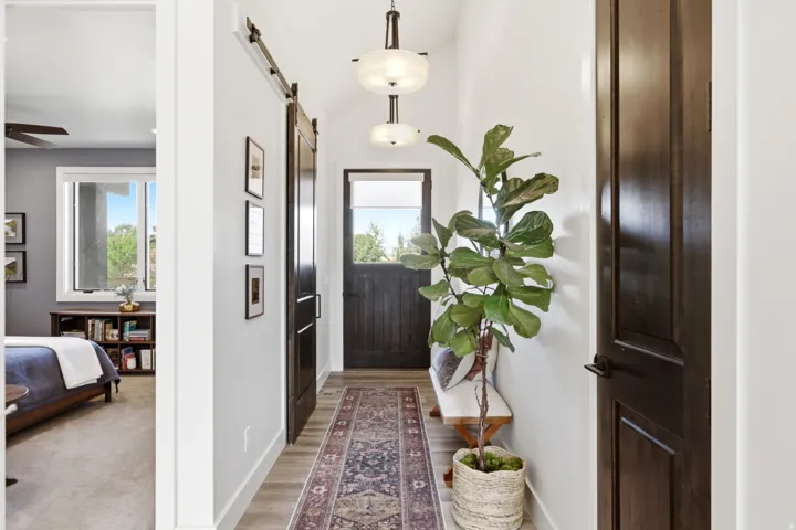 Wood-finish flooring, dark wood-tone barn door, and a paneled entry door with transom window