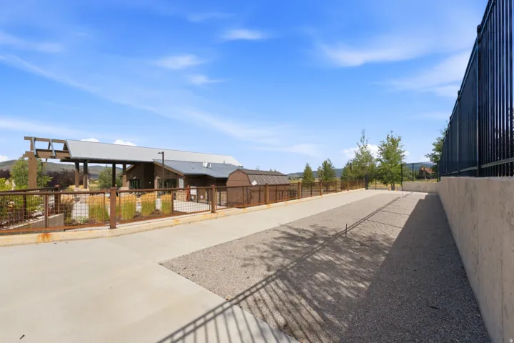Integrated concrete pathway with a central gravel strip, bordered by a black metal fence and a concrete retaining wall
