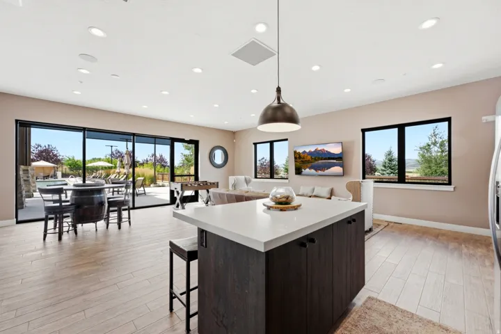 Spacious interior featuring a large kitchen island with a light-toned countertop, wood-finish flooring, and recessed lighting