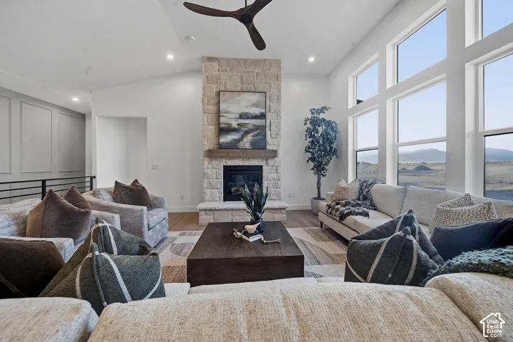 Spacious great room anchored by a floor-to-ceiling brick fireplace with a custom wood mantel, hardwood flooring throughout, and expansive multi-panel windows framing panoramic mountain and valley vistas
