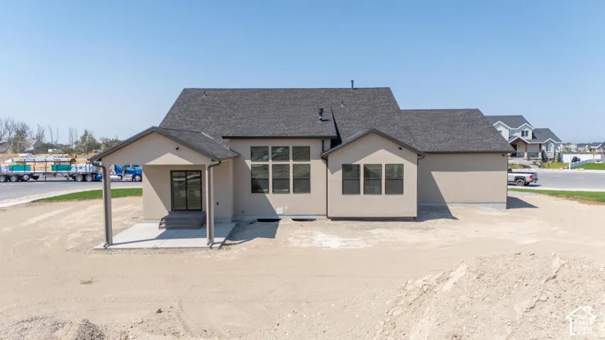 Stucco exterior with a dark shingle roof