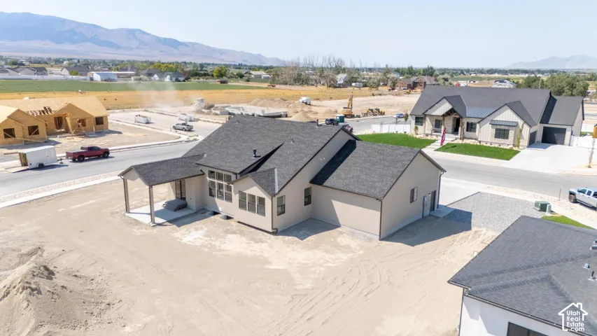 Newly constructed residence featuring a covered patio, multiple windows, and a dark shingle roof