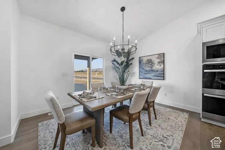 Vaulted ceiling, contemporary chandelier, wood-finish flooring, built-in double ovens, and a built-in microwave