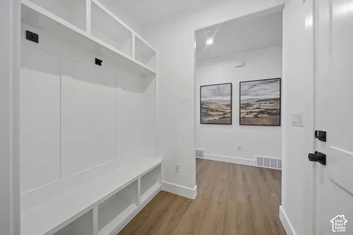 Built-in storage bench with overhead shelving, wood-finish flooring, recessed lighting, and a paneled entry door with matte black hardware