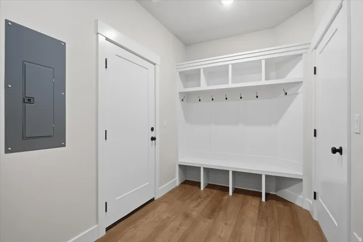 Built-in entryway storage with hooks and cubbies, LVP flooring, white paneled door, and neutral wall paint