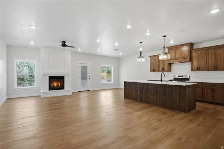 Spacious open-concept living area featuring LVP flooring, a white mantel fireplace and ceiling fan.