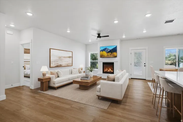Open-concept living area featuring wood-finish flooring, recessed lighting, and a white fireplace with a media niche