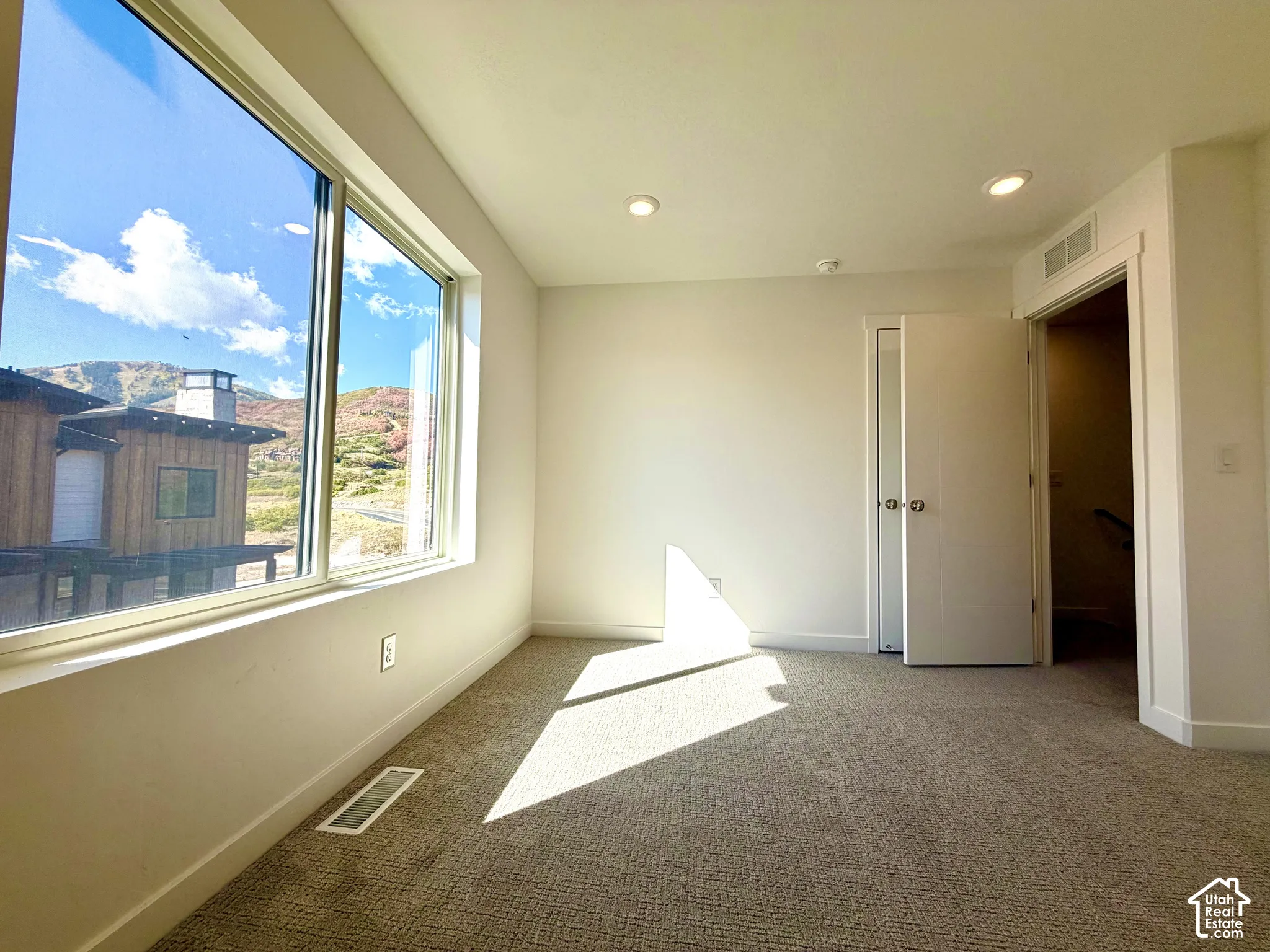 Recessed lighting, light-colored walls, and carpeted flooring