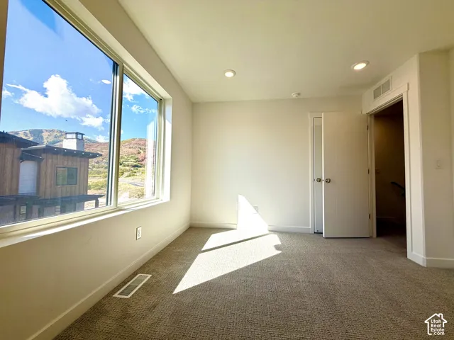 Recessed lighting, light-colored walls, and carpeted flooring