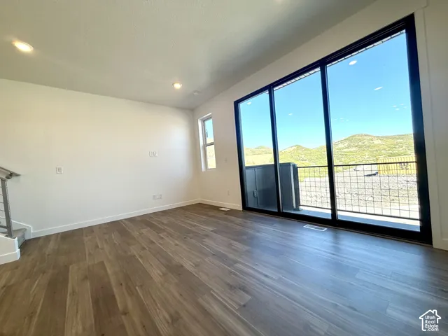 Expansive room featuring wood-finish flooring, recessed lighting, a large sliding glass door, and a full-height window