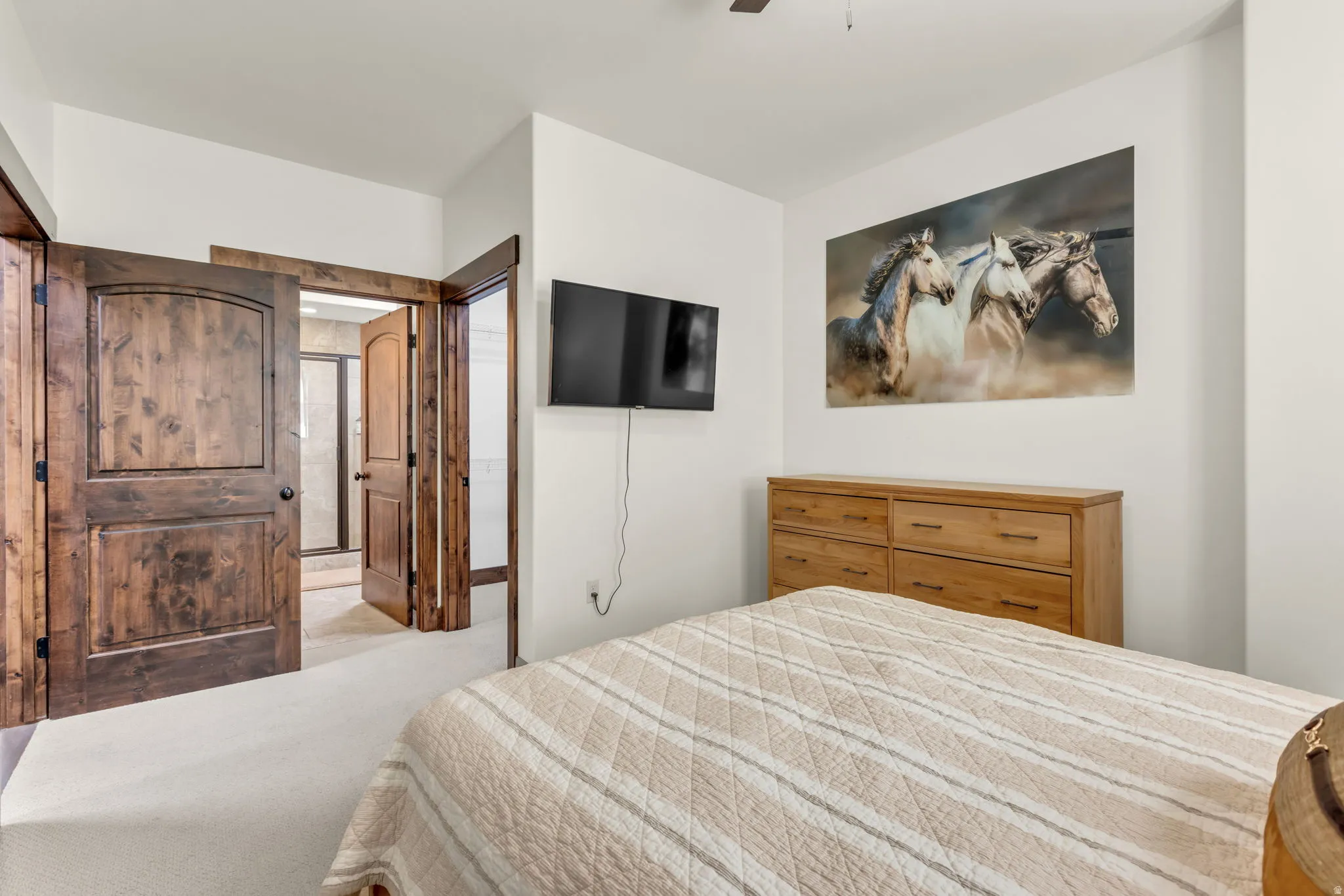 Two-panel wood doors with arched detailing, light-colored carpet, and an interior ceiling fan