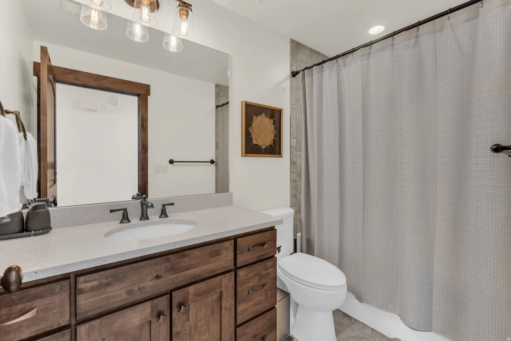 Wood-finish vanity with an integrated sink, light-colored countertop, and dark-toned faucet
