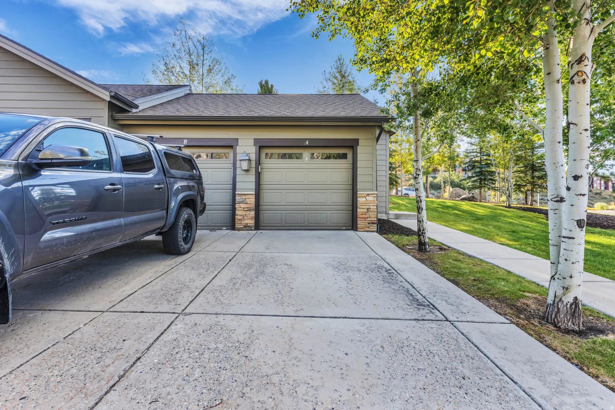 Attached two-car garage with overhead doors and stone veneer accents