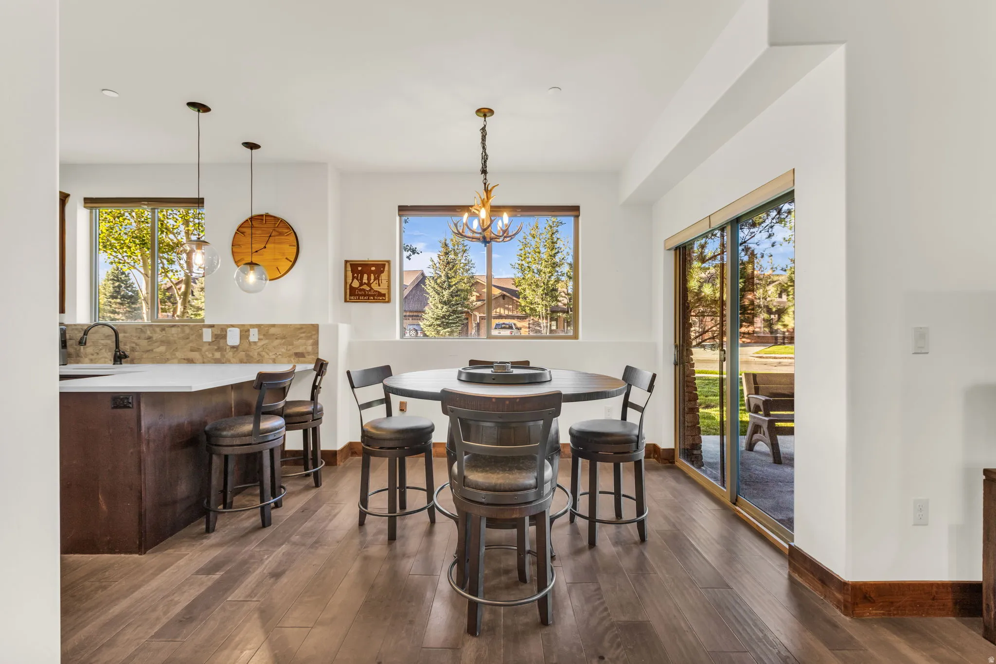 Wood-finish flooring, white walls, built-in breakfast bar with a light-toned countertop, and sliding glass patio doors