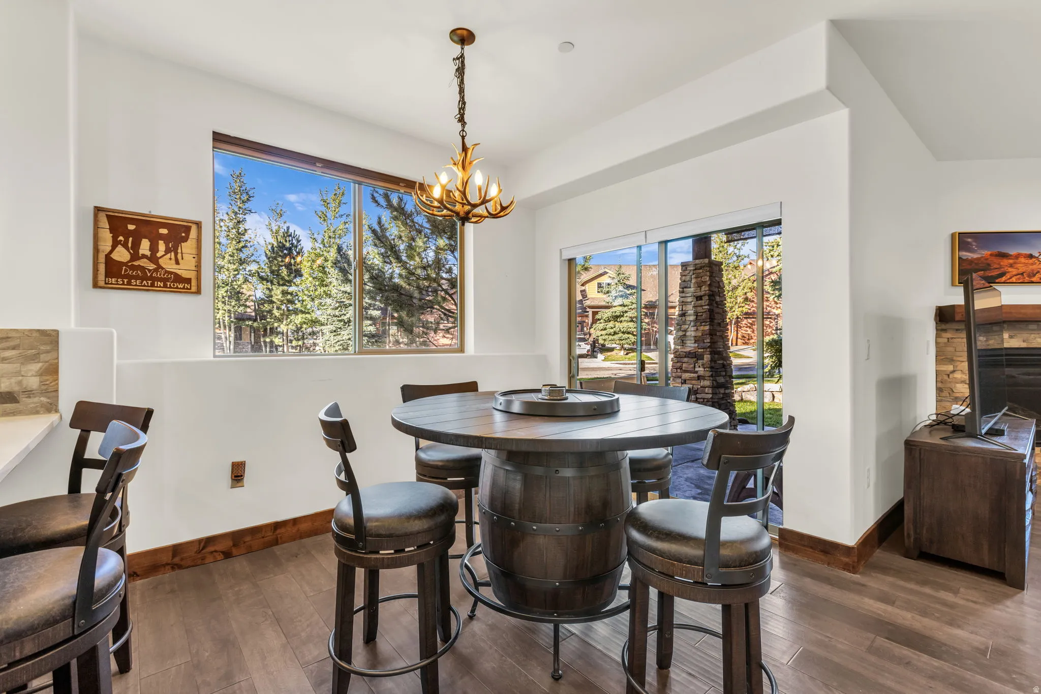 Wood-finish flooring, full-height windows, a sliding glass door, and a stone-clad fireplace