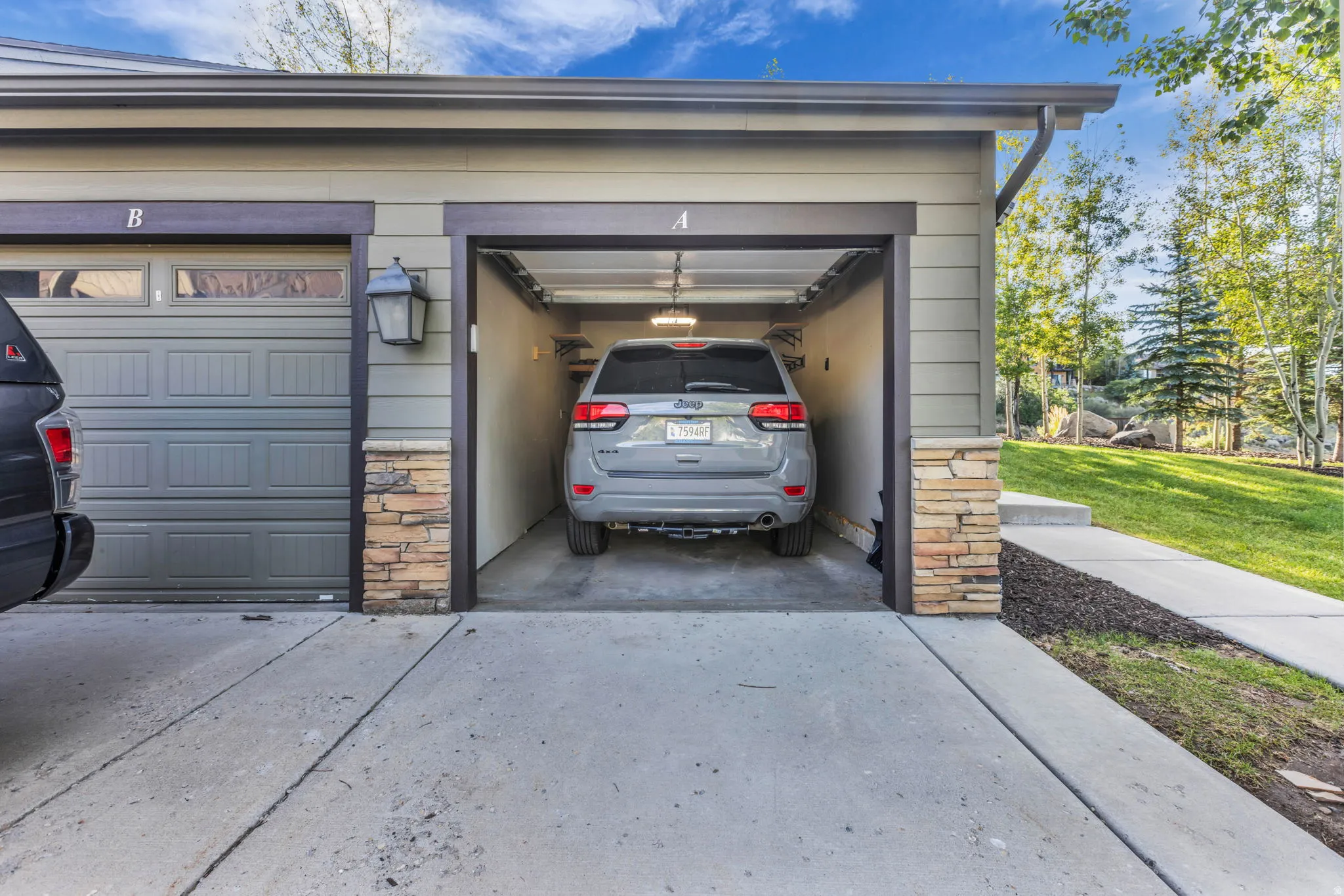 Two-car attached garage with concrete driveway and stone veneer accents