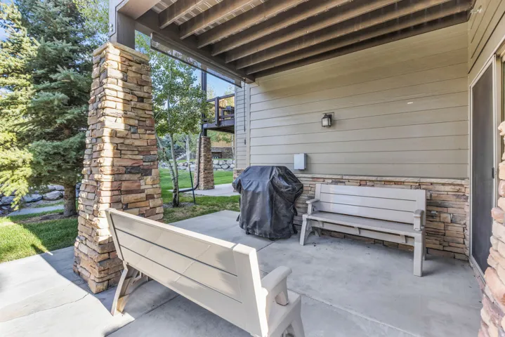 Covered patio featuring a concrete surface, stone-clad support columns, and horizontal siding