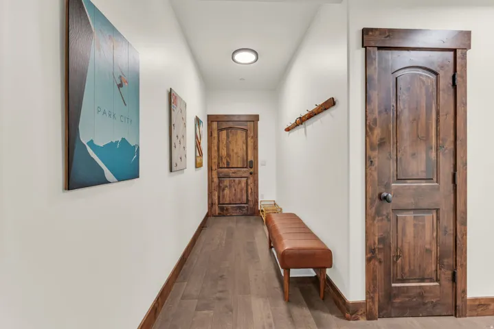 Hallway featuring wood-finish flooring, solid wood doors with arched panels, and a flush-mount ceiling light