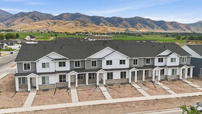 Townhome row with light gray siding, white trim, and stone accents