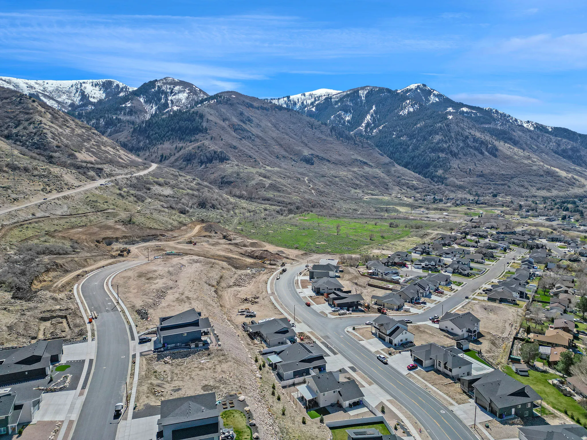 New construction homes with paved streets and sidewalks, against a backdrop of snow-capped mountains