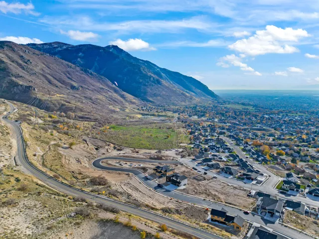 Expansive mountain range backdrop, established neighborhood with numerous homes, winding paved roads, developed residential lots, and broad scenic landscape